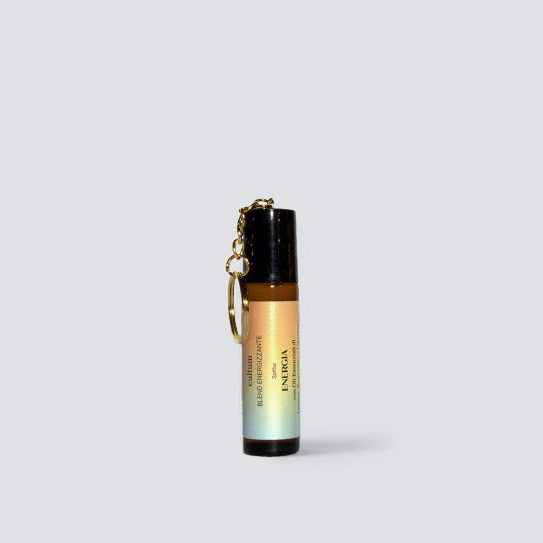 Roll-on botanico aromaterapico Energia di Cultum, ripreso su superficie in legno con ciondolo dorato. Formulazione energizzante con oli essenziali di limone, rosmarino e cipresso, pensata per aumentare vitalità, concentrazione e chiarezza mentale.
