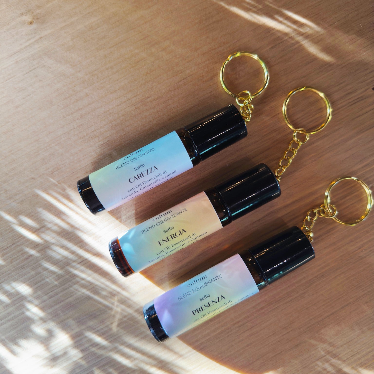 Immagine dei tre roll-on botanici Cultum – Carezza, Presenza ed Energia – disposti in verticale, con packaging minimale, tappo con catenella per attaccarlo alla borsa.